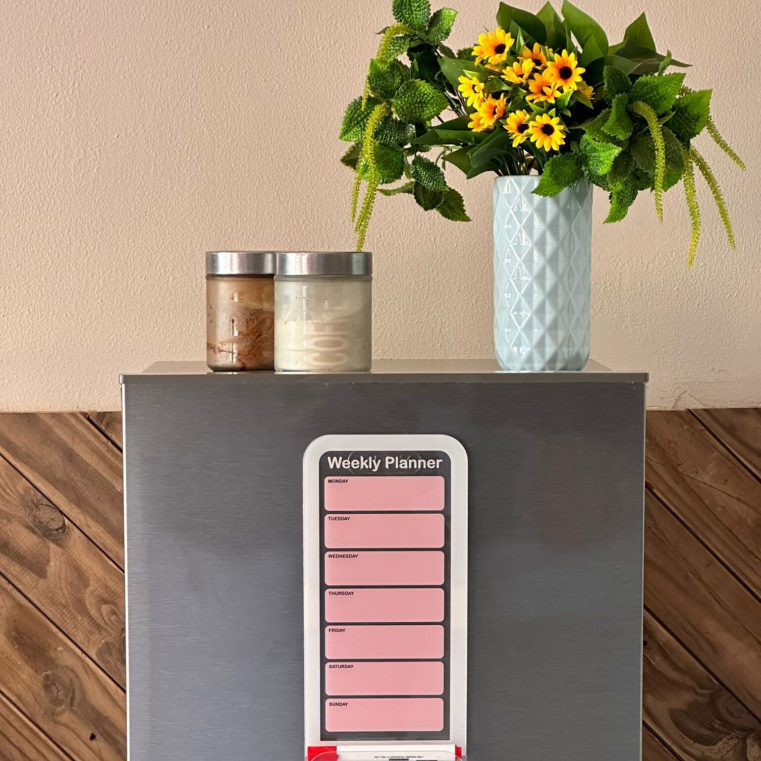 Pink weekly planner on a fridge with flowers
