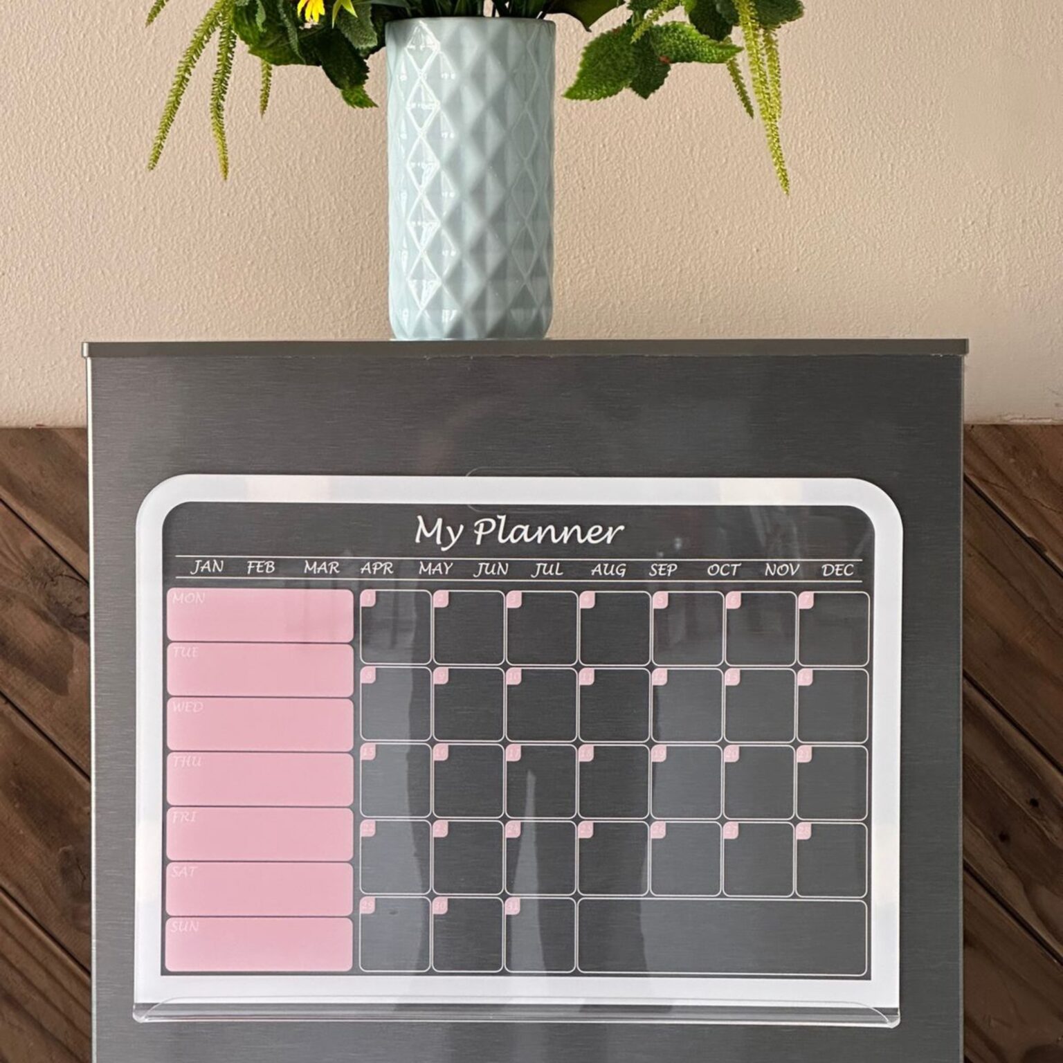 Pink and grey monthly planner on a fridge