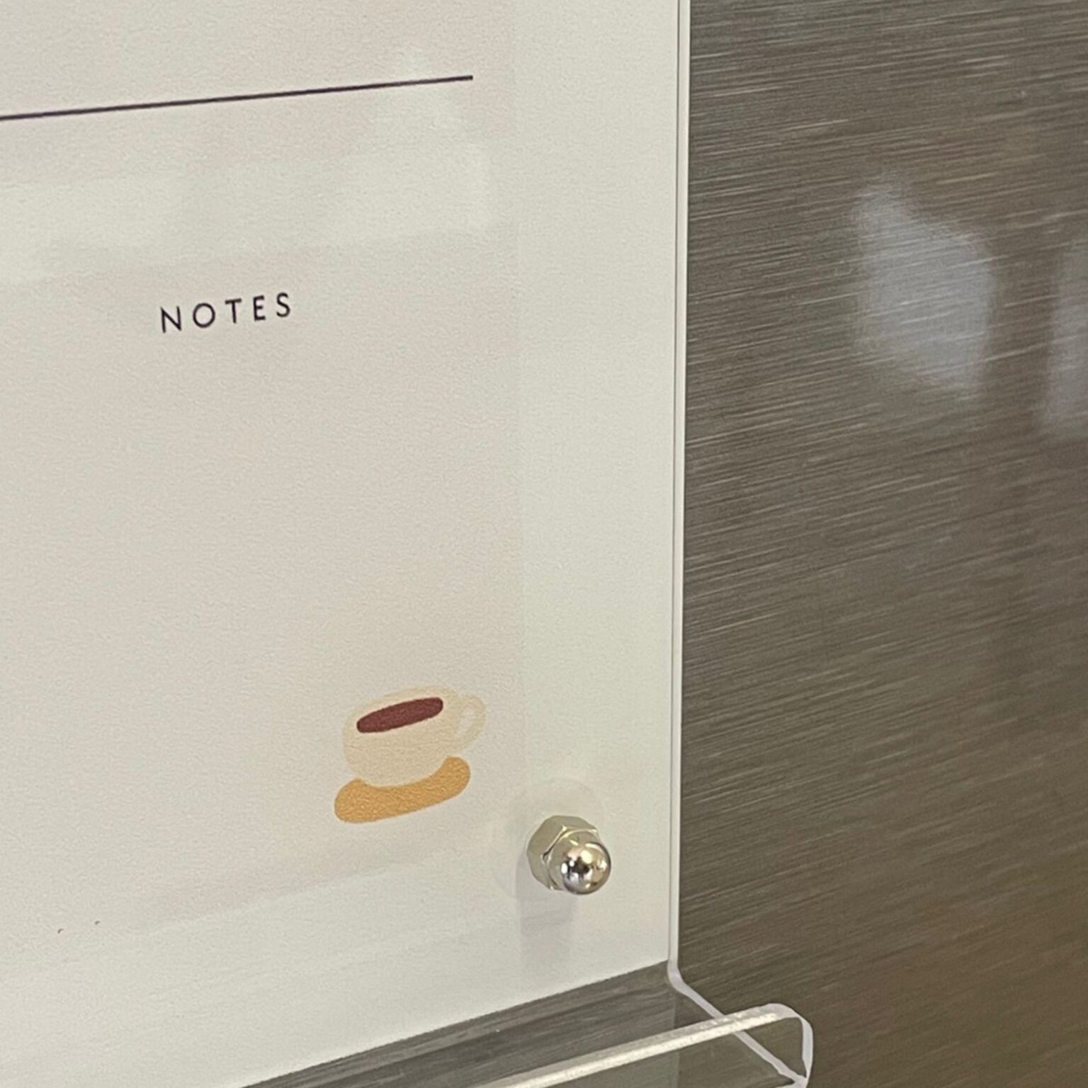 Silver stand-off pin detail on an ivory notes board